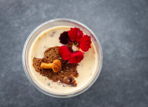 Creamy Chantarellesoup from top, garnished with a red flower and pickled mushroom